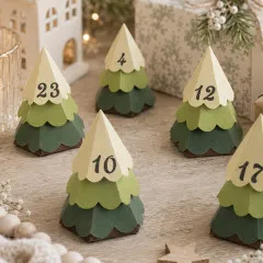 Fünf gestanzte 3D-Weihnachtsbaum-Schachteln aus grünem Papier mit Zahlen als Adventskalender auf Holztisch