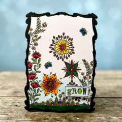Schwarz gerahmte Karte mit Mandala-Blüte, Stern, roten Blüten, Ranken und Etikett grow