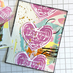 Mixed-Media-Seite mit pinkfarben gestempelten Herzen, Farbflächen und Spritzern