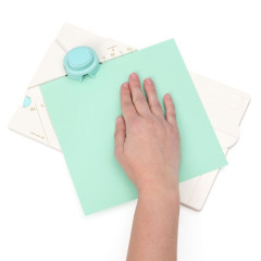 Hand positioniert grünes Papier auf türkisem Locher des Gift Box Punch Boards