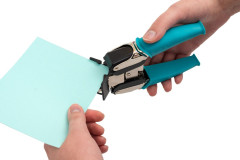 Corner Chomper wird von Hand verwendet zum Abrunden von Papierecken, türkise Silikongriffel sichtbar