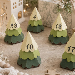 Fünf gestanzte 3D-Weihnachtsbaum-Schachteln aus grünem Papier mit Zahlen als Adventskalender auf Holztisch