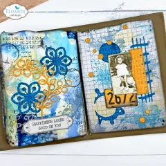 Anwendungsbeispiel: blau-oranges Journal-Doppelseite mit Blüten-Stanzformen, Vintage-Kinderfoto und Nummernschild „2672“.