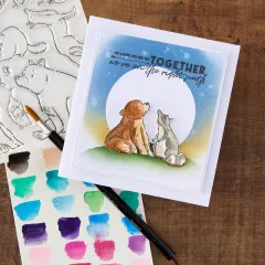 Anwendungsbeispiel: aquarellierte Bär-und-Wolf-Szene neben Stempelbogen, Pinsel und Aquarellfarbpalette.