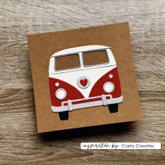 Kraftpapier-Karte mit rot-weißem Hippie Bus aus Papier und Glitzer-Stoßstange auf Holzuntergrund