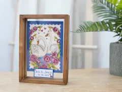 Gerahmtes Hochzeitsbild mit zwei Schwänen, Rosen und individuellem Namens- und Datumsschild.