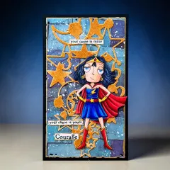 Blaue Karte mit goldener Mond-und-Sterne-Stanzform, gestempelter Superheldin-Figur und Wortsticker „Courage"