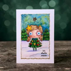 Beispielkarte im Goldrahmen mit der Mädchenfigur vor zwei Tannenbäumen und Nachthimmel, Schriftzug 'it's sParkle season'.