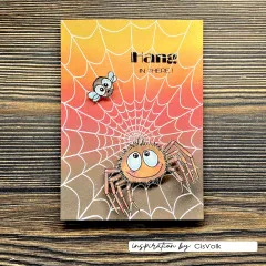Orange-gelbe Karte mit gestempeltem Spinnennetz, kolorierter Spinne und Fliege sowie Schriftzug 'Hang in there'