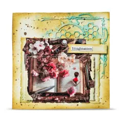 Gelb-türkise Karte mit Zahnrad-Stanzteilen um das aufgeschlagene Buch mit Kirschblüten, mit Wortsticker „Imagination"