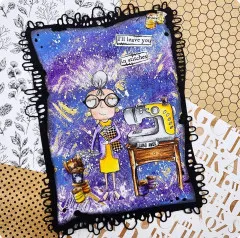 Lila-blaue Karte im Galaxie-Look mit der Näh-Figur, Nähmaschine und Garnrollen