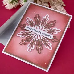 Weihnachtskarte mit goldfarbener und weißer geschichteter Schneeflocke sowie dem Schriftzug 'Snowflake Kisses' auf rosa Hintergrund.