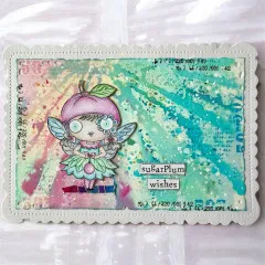 Beispielkarte mit der Pflaumen-Feenfigur vor pastellfarbenem Aquarell-Hintergrund, Schriftzug 'sugarPlum wishes'.
