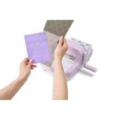 Hände zeigen gestanzte und geprägte Papierkarten neben Sizzix Big Shot Lilac mit Texturergebnissen