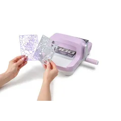 Hände halten gestanztes Papier mit Blumenmuster neben Sizzix Big Shot Lilac Stanzmaschine