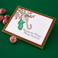 Grüne Weihnachtskarte mit koloriertem Maxwell-Motiv und Schriftzug „Unwrap the Magic – Merry Christmas!“