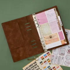 Aufgeschlagenes Ringbuch mit eingehefteter Monatsregister-Seite "Feb" und Vintage-Papieren