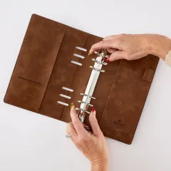 Zwei Hände öffnen die 6-Ring-Mechanik des leeren Ringbuchs