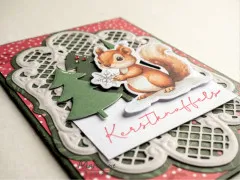 Nahaufnahme der Weihnachtskarte mit Eichhörnchen, Schneeflocke und Spitzenrahmen.