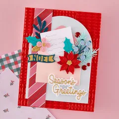 Detailaufnahme der Weihnachtskarte mit Weihnachtsstern, Blüten, Tannenzweig und dem Schriftzug 'Season's Greetings'.