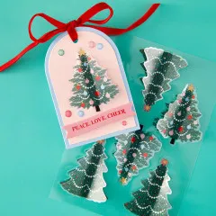 Weihnachtskarte mit aufgeklebtem Weihnachtsbaum-Sticker, Spruchband „Peace, Love, Cheer“ und roter Schleife