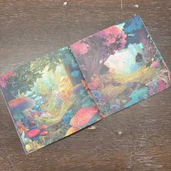Aufgeschlagene Doppelseite mit zwei Designs eines farbenfrohen Fantasy-Waldes mit rosa-blauen Bäumen und roten Pilzen.