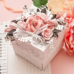 Rosa Explosionsbox mit großen Rosen, Blättern und Schleifen-Dekoration in Nahaufnahme
