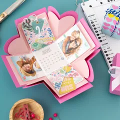 Explosion Board mit Rosa-Herzschachteln, aufgeklappter Kalender und dekorativen Elementen, Draufsicht