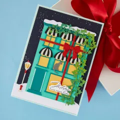 Handgemachte Weihnachtskarte mit verzierter Ladenfassade, Schleife und Laterne