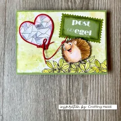 Grün-goldene Karte „Post(z)egel" mit herzförmigem Briefkuvert-Anhänger und Igel vor Aquarell-Hintergrund.