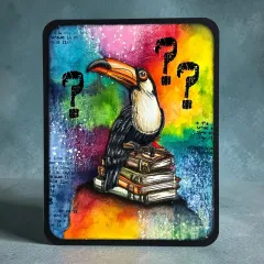 Bastelkarte mit Tukan auf Stapel alter Bücher und bunten Aquarellfarben