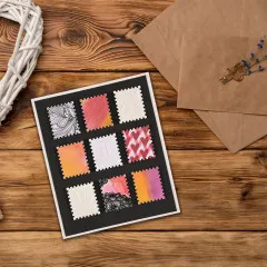 Kunstvolle Grußkarte mit neun gestanzten Briefmarken-Motiven auf schwarzem Untergrund, Holztisch mit Zubehör