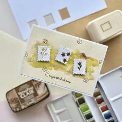 Glückwunschkarte mit drei gestanzten weißen Briefmarken und bemaltem gelbem Aquarell-Hintergrund, Motivstanzer im Bildrand