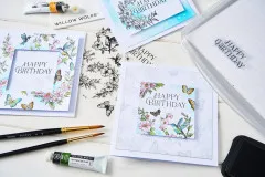 Nahaufnahme der aquarellierten Grußkarte mit Kolibri, Blüten und Schmetterlingen