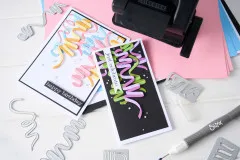 Nahaufnahme der fertigen Grußkarten neben den Metallstanzformen und farbigem Cardstock