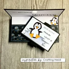 Aufklappbare Karte mit geprägten Pinguinen und koloriertem Pinguin auf Holzuntergrund
