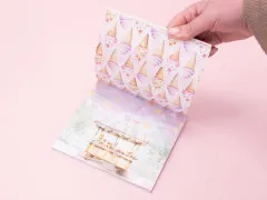 Aufgeschlagener Papierblock mit Eistüten-Musterseite über Eisstand-Motiv