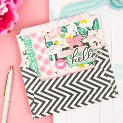 Zwei Slimline-Karten mit Liebes- und Glückwunschmotiven neben Punch Board und rosa Schere auf Pastelluntergrund
