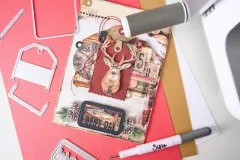 Winterliches Tag-Projekt mit Hirschmotiv, Uhr und Rahmen Best Day, daneben Stanzschablonen und Walze