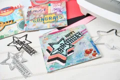 Nahaufnahme von Stanzformen, farbigem Cardstock und den fertigen Wortmotiv-Karten