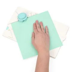 Hand positioniert grünes Papier auf türkisem Locher des Gift Box Punch Boards