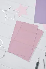 Fliederfarbene Sizzix Cutting Pads auf weißem Holztisch mit Stanzschablonen und Papiersternen