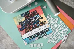 Karte mit schwarzen Stackers auf buntem Hintergrund und Schriftzug Filled with Wonder, daneben die Stanzen