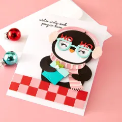 Fertige Weihnachtskarte mit Pinguin-Figur, Geschenk und rot-rosa kariertem Hintergrund