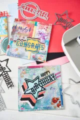 Nahaufnahme der Metallstanzformen neben fertig gestalteten Geburtstags- und Glückwunschkarten