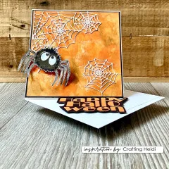 Steckkarte mit orangefarbenem Strukturhintergrund, dreidimensionaler Spinne, Spinnennetz-Stanzformen und Schriftzug „Happy Halloween".