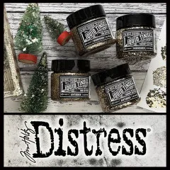 Mehrere Dosen Tim Holtz Distress Liquid Tinsel in Antiqued und Tarnished neben Vintage-Dekoelementen und Tim Holtz Distress Logo