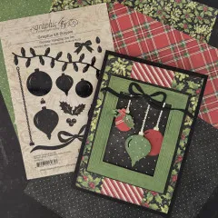 Geöffnete Verpackung des Holiday Hanging Die Sets neben zwei gestalteten Grußkarten mit farbigen Motiven auf Patchwork-Untergrund