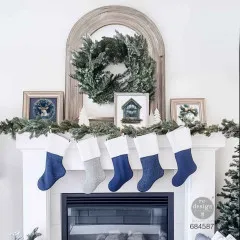 Kaminsims dekoriert mit Tannengrün, Weihnachtssocken und gerahmten Quiet Country Blue Motiven.