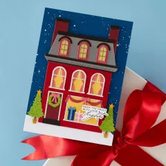 Handgemachte Weihnachtskarte mit einem roten Stadthaus und dekoriertem Dach